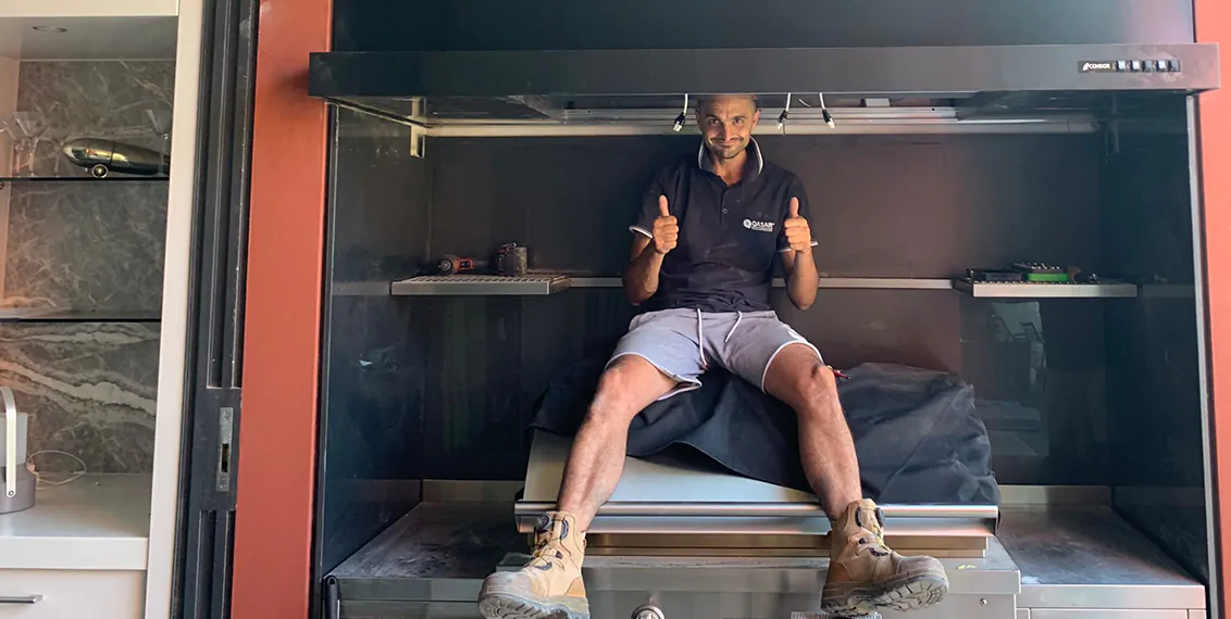 Peter in the middle of cleaning a rangehood and smiling with his thumbs up.