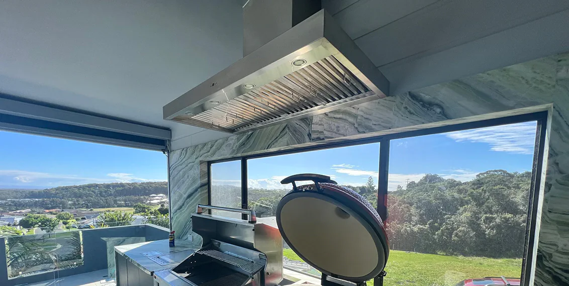 A beautiful large stainless steel alfresco style rangehood in an outdoor kitchen