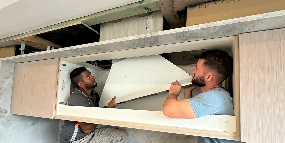 Two of our electricians setting up a rangehood in a kitchen