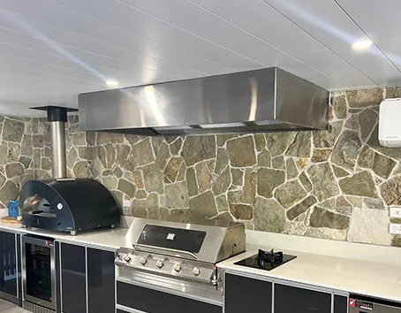 A beautiful stainless alfresco rangehood against a stone wall