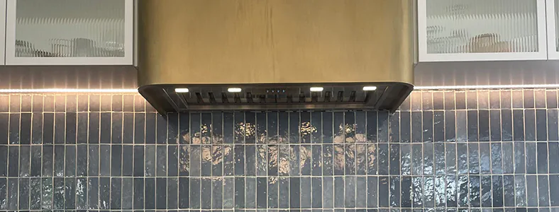 A beautiful golden bronze canopy rangehood in a stylish kitchen