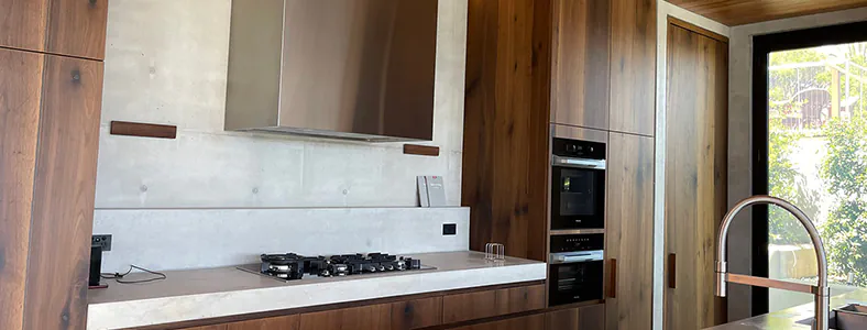A stainless steel canopy rangehood in a wooden kitchen, showcasing a blend of modern and rustic design