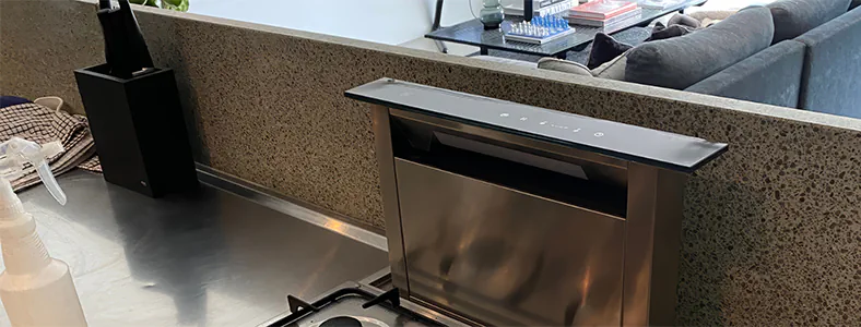 A stylish small downdraft rangehood on a stainless steel cooktop, providing efficient ventilation in compact spaces