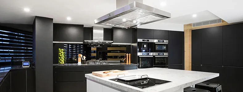 A lovely modern stainless steel island rangehood in a black kitchen, providing a striking contrast and efficient ventilation