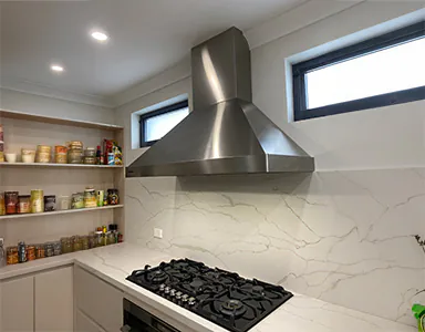 A large new wall mounted stainless steel rangehood in a simple kitchen, combining functionality with a minimalist design