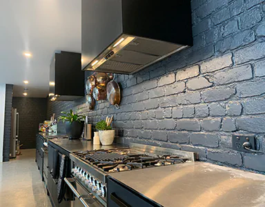 A stylish black wall mounted rangehood in a modern organic styled kitchen, blending functionality with aesthetics