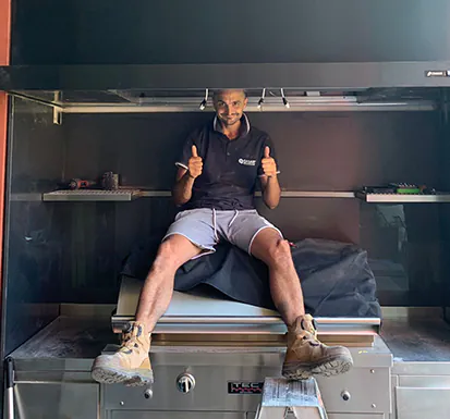 Peter in the middle of cleaning a rangehood and smiling with his thumbs up.
