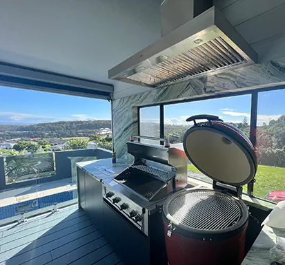 A beautiful large stainless steel alfresco style rangehood in an outdoor kitchen