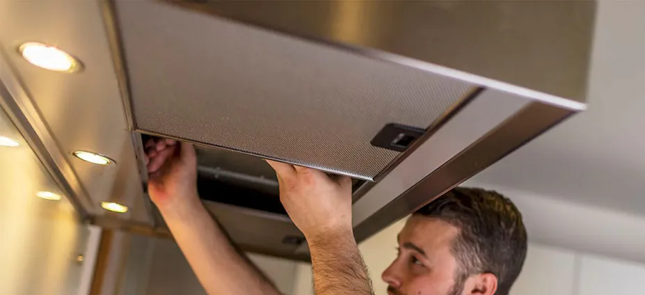 A technician installing a new rangehood exhaust fan